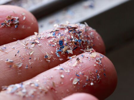 Nahaufnahme einer Hand, auf der man Mikroplastik-Reste sieht